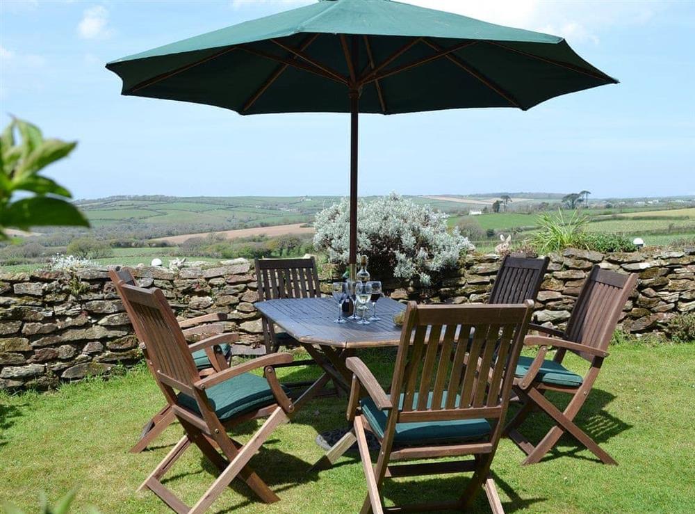 A large table with chairs is placed in an ideal location to take advantage of the sunshine and the view at Coachmans Cottage in White Cross, near Newquay, Cornwall