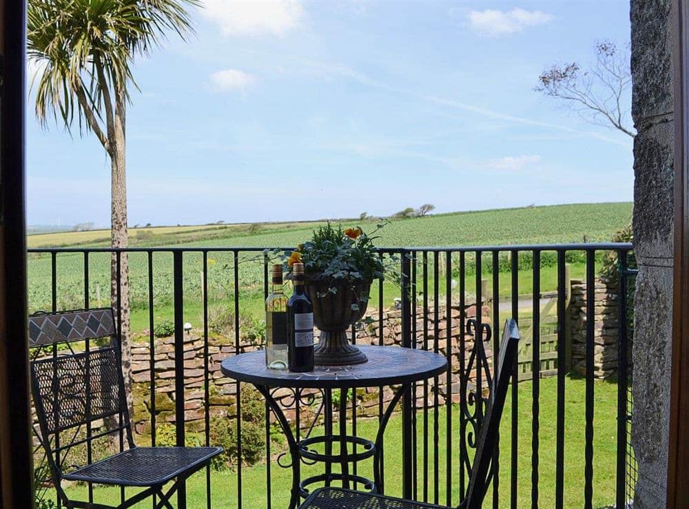 A table and chairs placed outside the living room makes a great place to enjoy the view and a glass of wine at Coachmans Cottage in White Cross, near Newquay, Cornwall