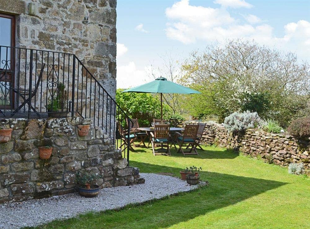 Sone steps lead down from a small patio to the private walled garden at Coachmans Cottage in White Cross, near Newquay, Cornwall