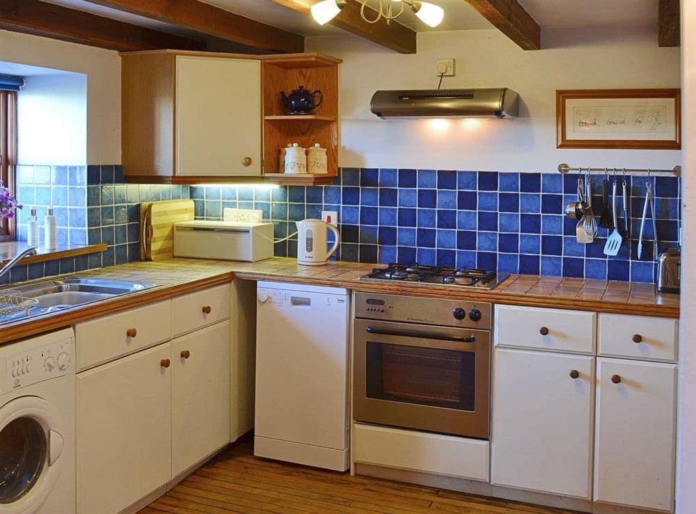 The contemporary half tiled kitchen is fited with up to date appliances to make mealtimes a pleasure, not a chore at Coachmans Cottage in White Cross, near Newquay, Cornwall