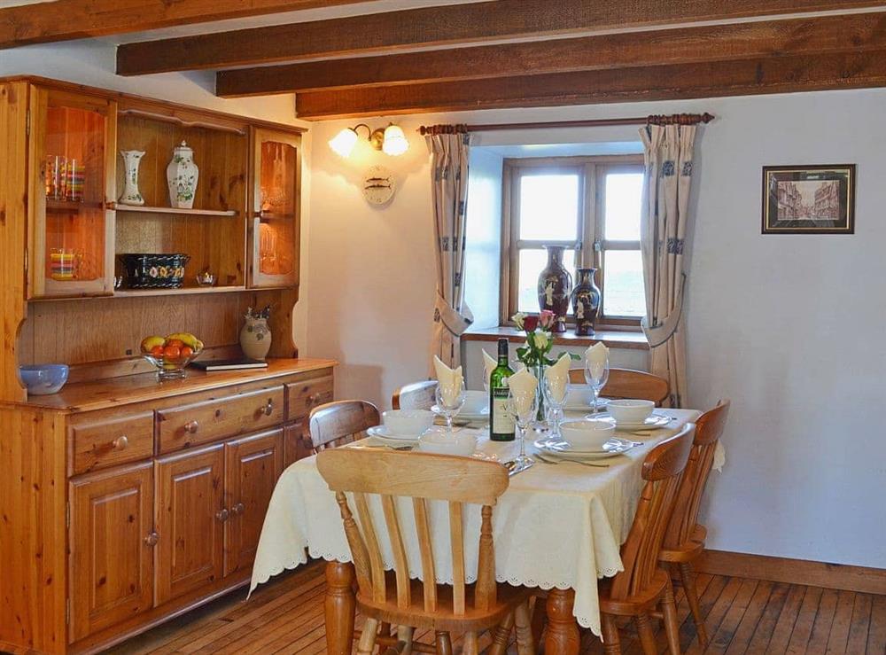 The farmhouse style table and dresser complement the dining area’s wooden floor and exposed beams at Coachmans Cottage in White Cross, near Newquay, Cornwall