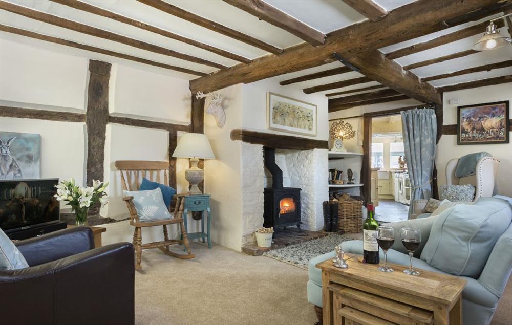 Sitting room with exposed beams, wood burning stove and raised dining area at Cobblers Cottage, Pembridge