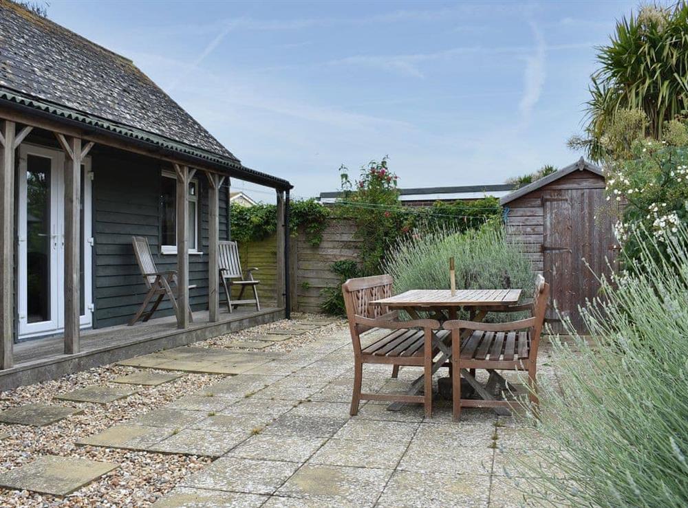 Paved rear garden with table and chairs at Cockle Cottage in Elmer, near Middleton on Sea, West Sussex