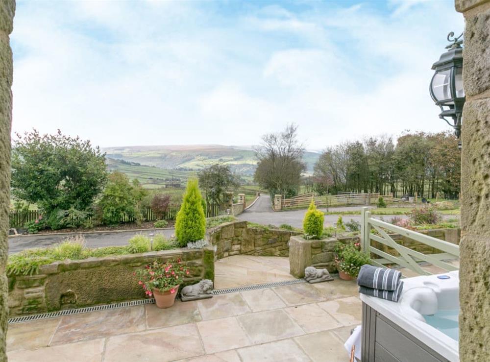 Luxurious hot tub sits on one side of the south-facing, flagstone patio with fantastic views at Commons Farm Cottage in Wadsworth, near Hebden Bridge, West Yorkshire
