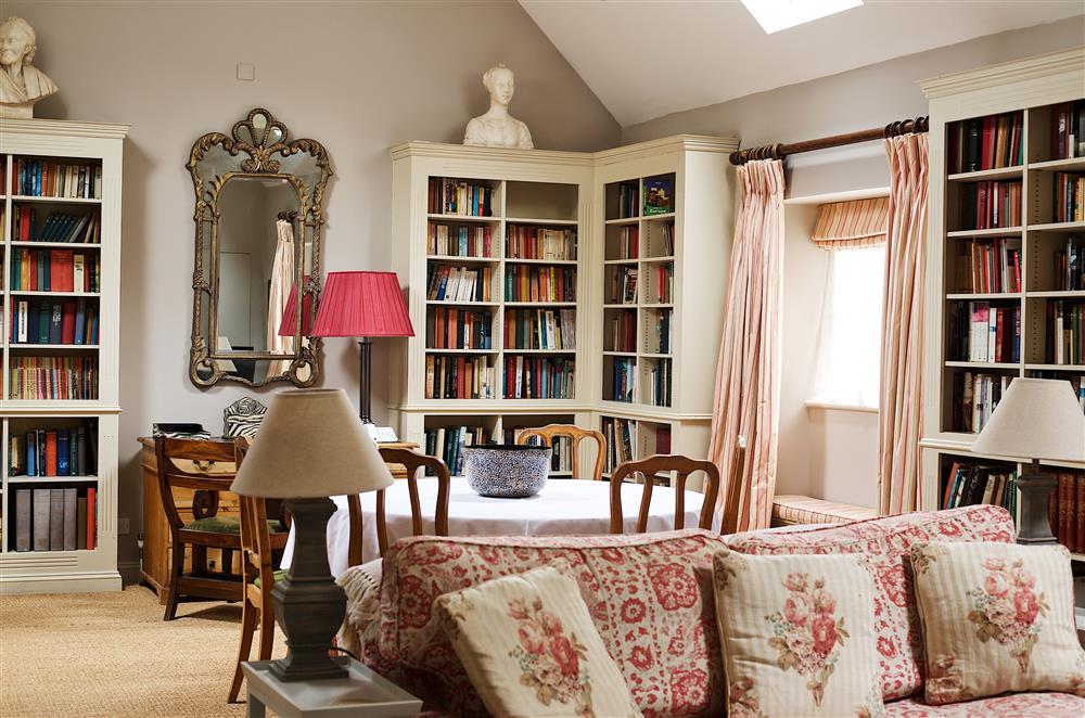 Bookcases perfectly frame the walls in the open-plan sitting and dining room at Cope Cottage, Bruern, near Chipping Norton
