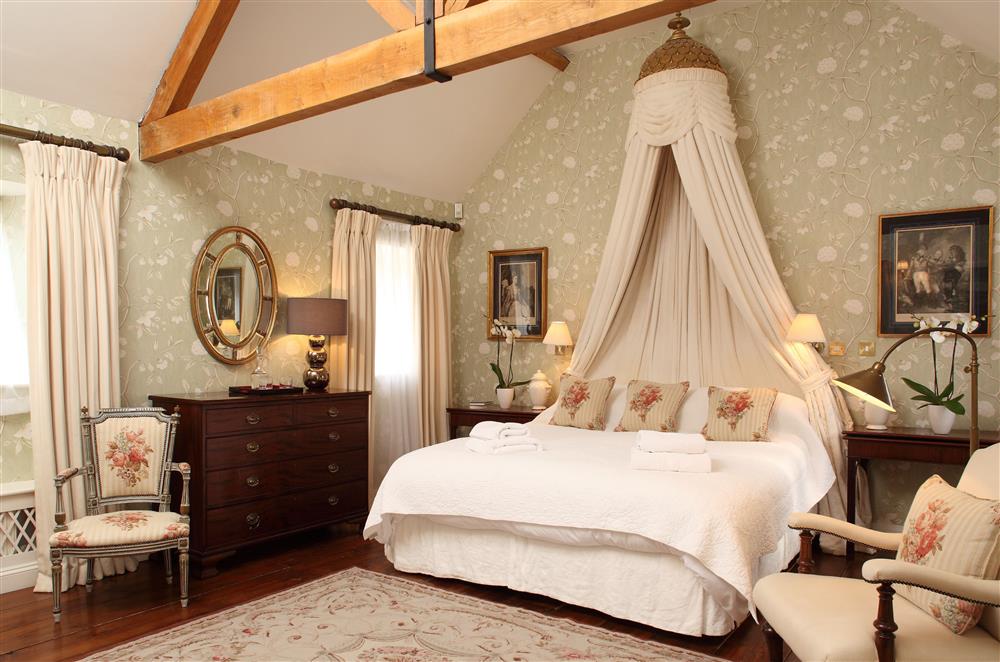 The bedroom enjoys exposed beams and polished dark wood floor at Cope Cottage, Bruern, near Chipping Norton
