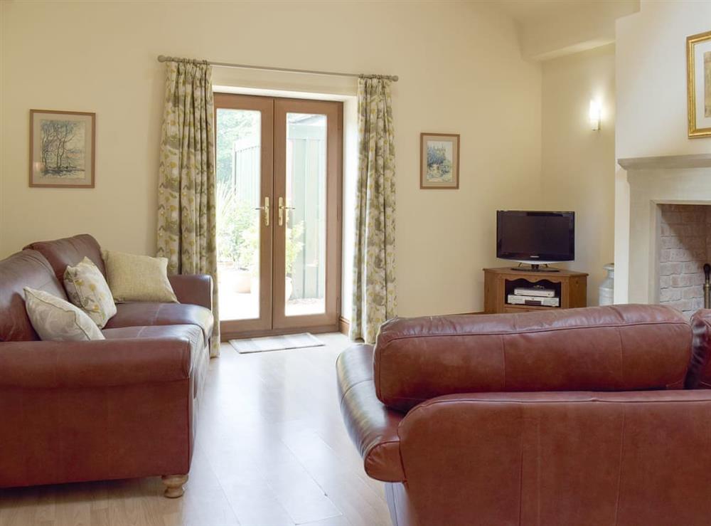 Attractive living area with French doors to patio at Woodpecker Cottage, 