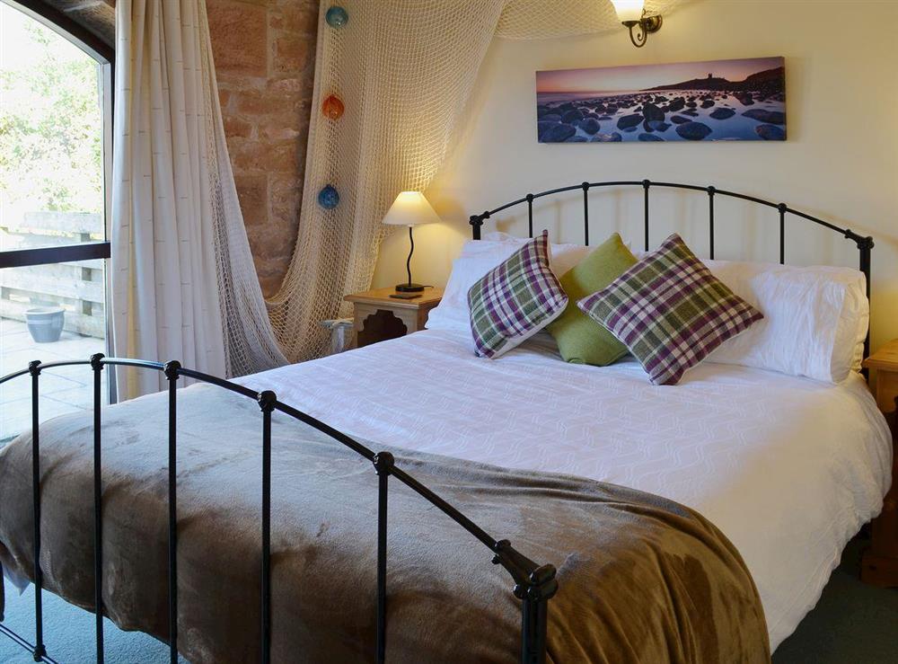 The double bedroom has a kingsize bed and exposed beams at Corn Cottage in Belford, Northumberland., Great Britain
