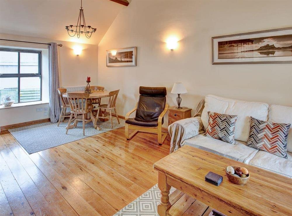 The wood-floored open plan living area with comfortable chairs and sofa at Corn Cottage in Belford, Northumberland., Great Britain