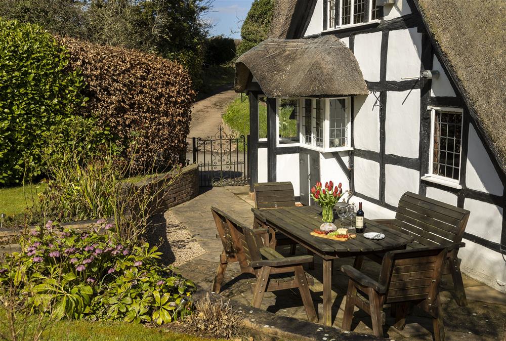Pretty, south facing garden with paved patio area, garden furniture and steps up to the lawn at Corner Thatch, Abbots Morton