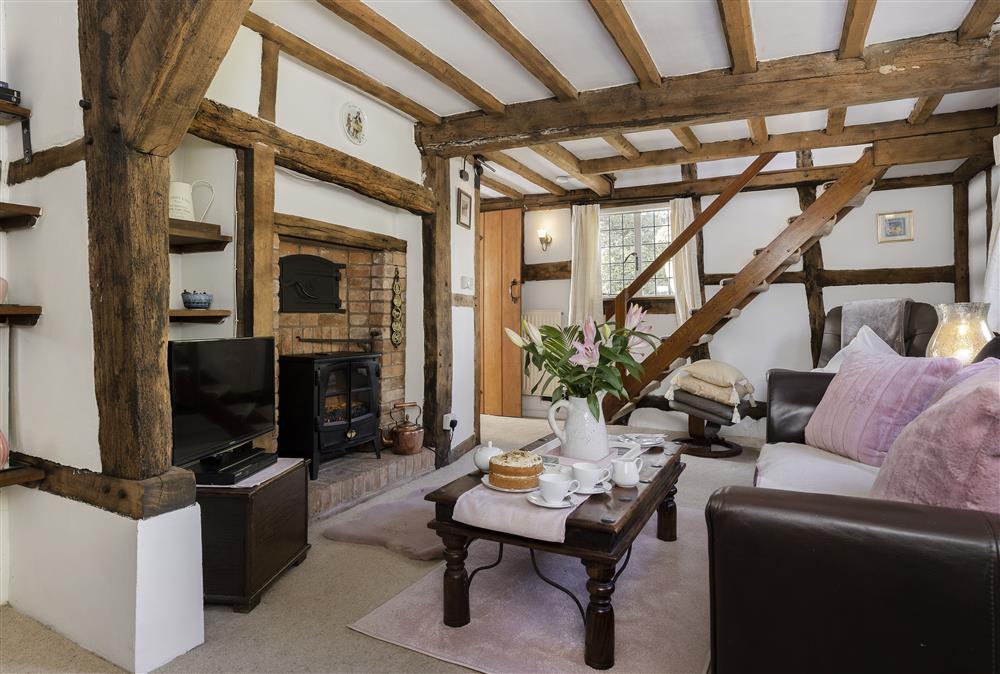 Sitting room with exposed beams, wood effect electric fire and original bread oven at Corner Thatch, Abbots Morton