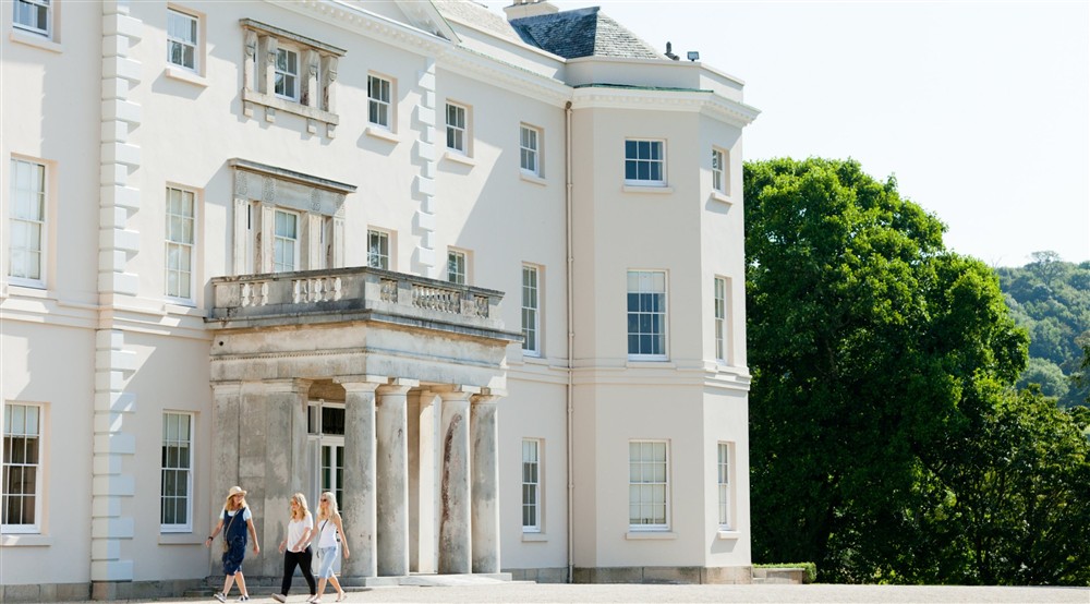 Three people walking past the entrance of Saltram House at Cotehele Engine Cottage in Calstock, Cornwall