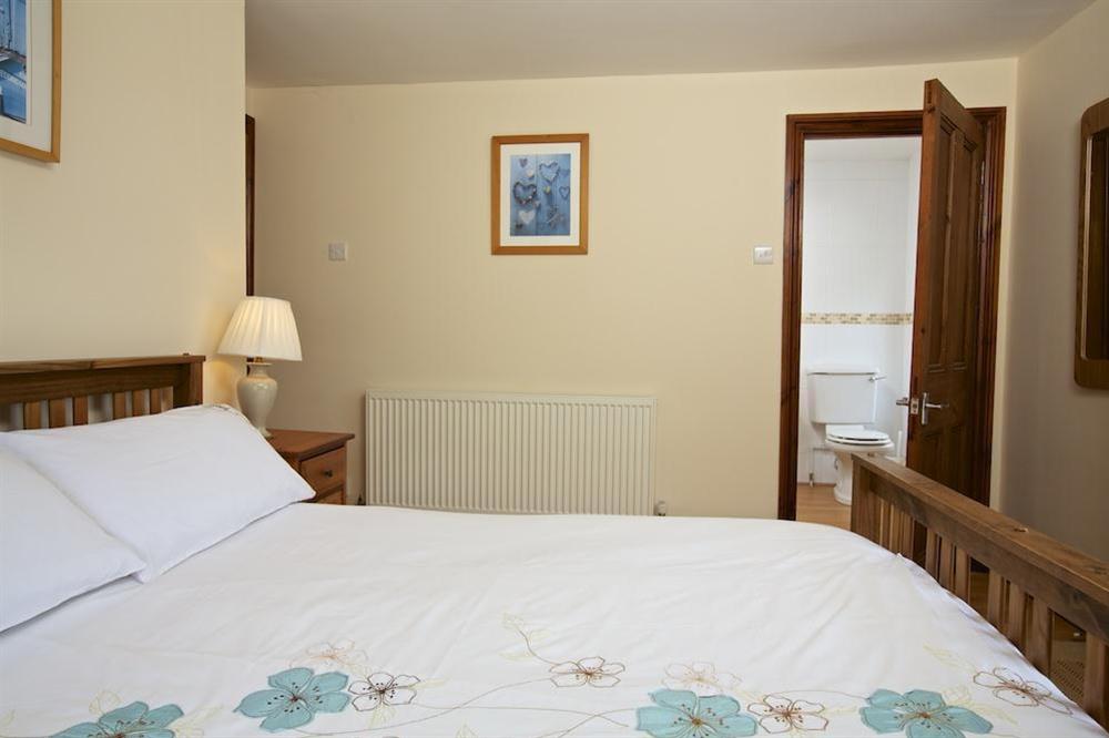 Master bedroom with King-size bed and en suite bathroom at Cove Cottage in Hope Cove, Nr Kingsbridge