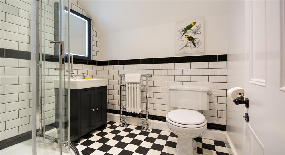 A black and white tiled room with shower cubicle, sink and toilet.