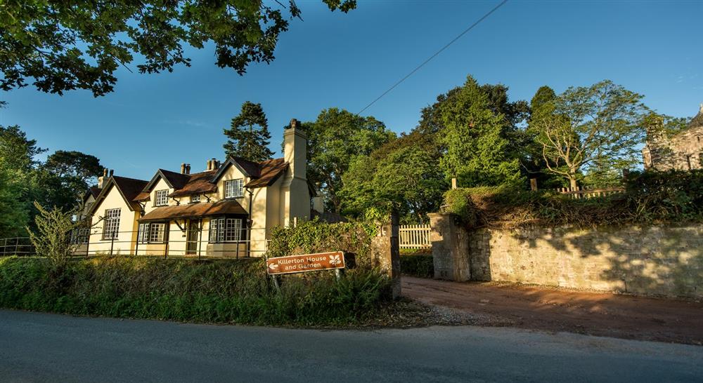 The exterior of Crabtree School House and Lodge, Devon. Taken from across the lane showing the front of the cottage and the greenery around it.