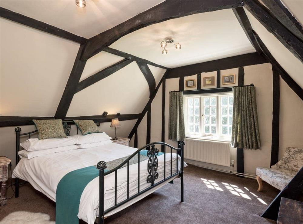 Double bedroom on second floor with original exposed timber joists and sloping ceiling at Cravens Manor in Henham, near Southwold, Suffolk