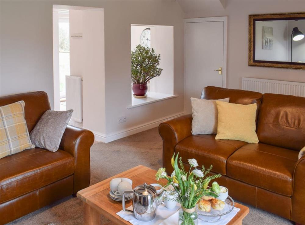 Beamed living room with comfortable leather sofas at Croft Cottage in Newholm, near Whitby, North Yorkshire