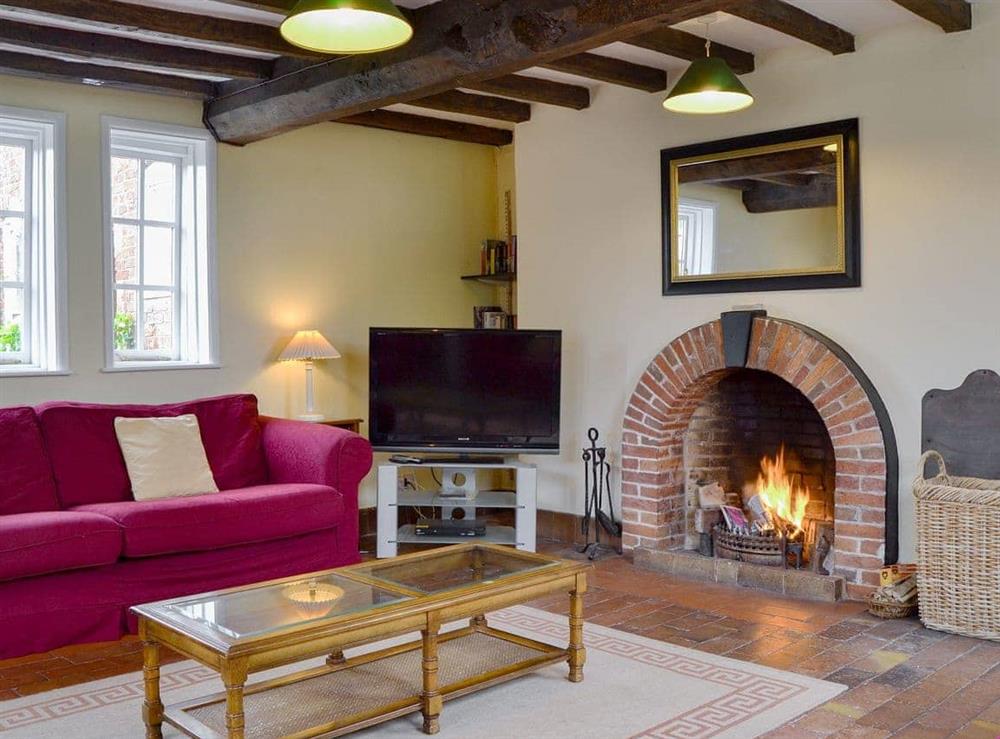 Characterful living room with beamed ceiling and an open fire with feature fireplace at Cronkhill Farmhouse in Attingham Park Estate, Nr Shrewsbury., Shropshire