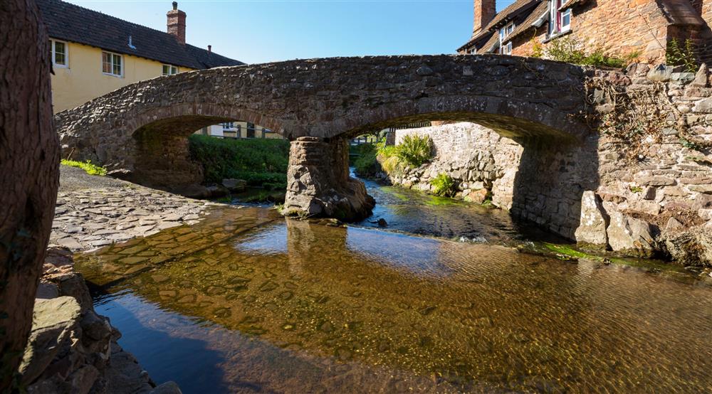 The medieval packhorse bridge crossing over River Aller in Allerford village near Cross Lane House, Somerset