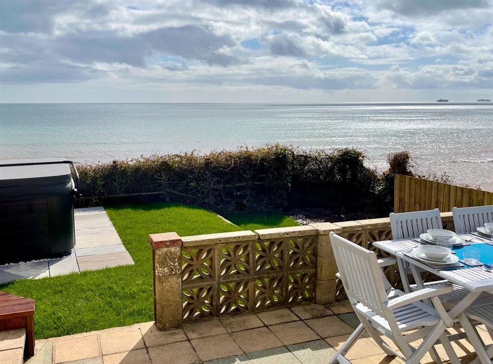 Step out of the kitchen onto the outdoor dining area complete with grassy lawn and breathtaking degree sea views at Crows Nest in Dawlish, Devon