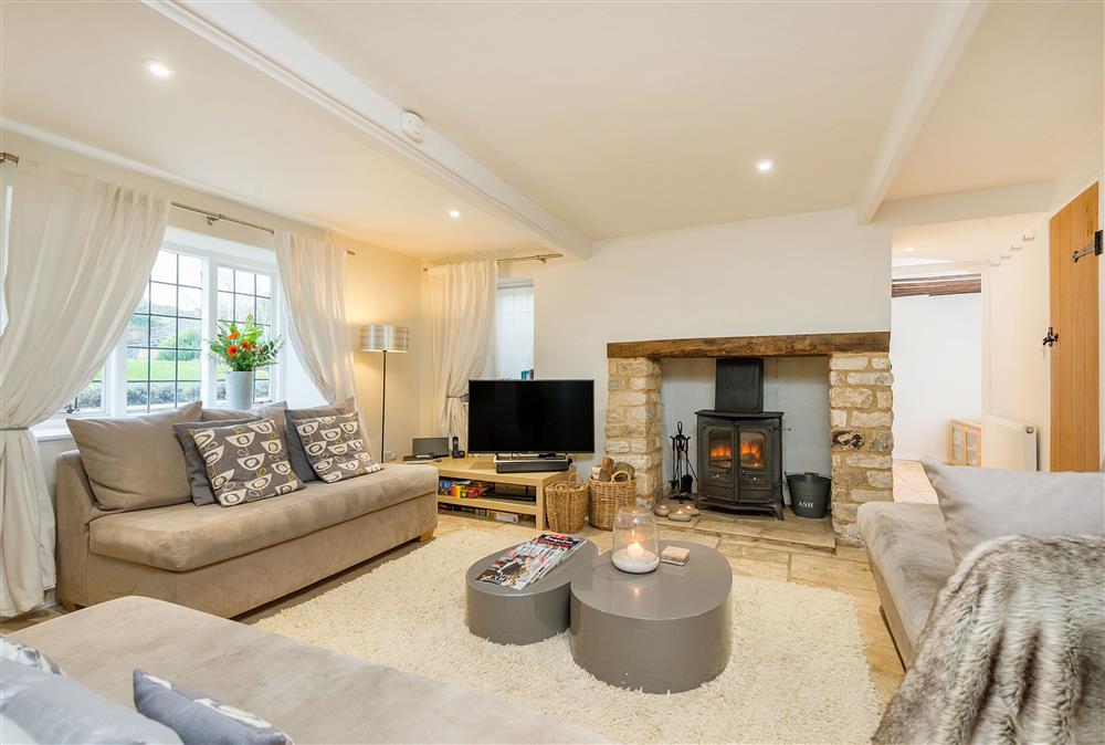 Sitting room with Cotswold stone fireplace and  wood burning stove at Culls Cottage, Southrop