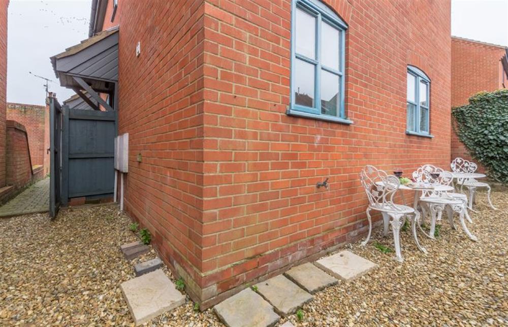 A courtyard garden has seating and an outside tap for cleaning muddy boots and dogs at Curlew Apartment, Wells-next-the-Sea