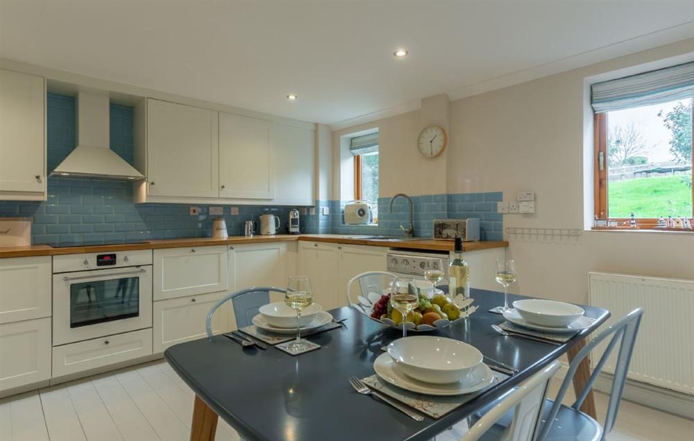 Large open-plan kitchen and dining area seating four guests at Curlews Cwtch, Roserrow