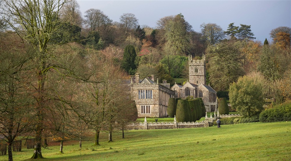 A view across parkland to the stone house and church at Cutmadoc in Bodmin, Cornwall
