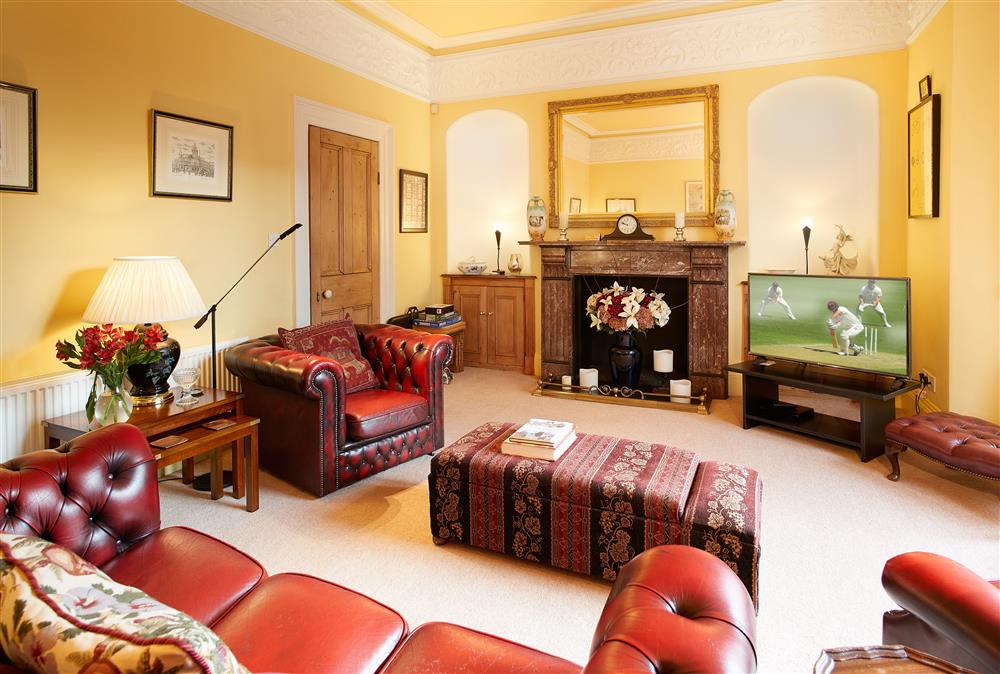 Sitting room with leather seating, decorative fire place and bay window
