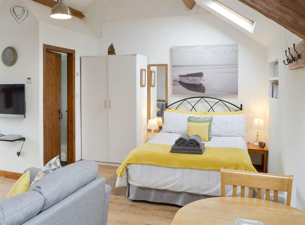 Double bed within studio-style living area at Daisy Cottage in Pwllheli, Gwynedd
