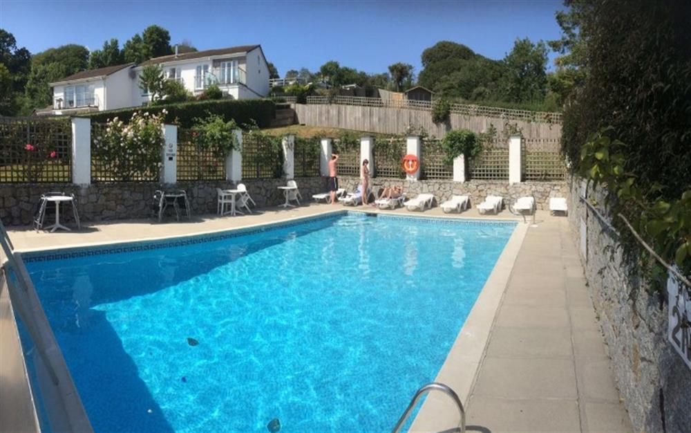 The heated swimming pool, with sun loungers and patio tables is accessed through the garden gate. at Demelza 1 in Helford Passage