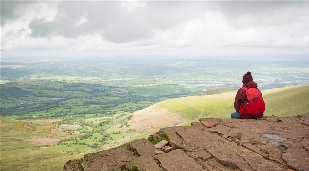 A hiker sitting looking at Dinefwr Deer Lodge in Llandeilo, Carmarthenshire
