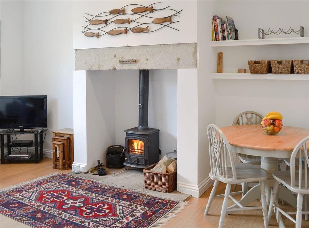 Spacious living/ dining room with wood burner at Dipper Cottage in Seahouses, Northumberland