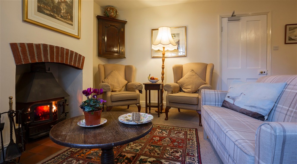 The sitting room with wood burner at Downhouse Farm Cottage in Bridport, Dorset
