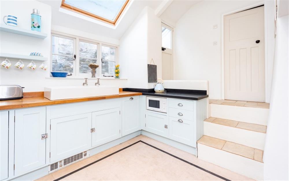 The kitchen with steps up to the main entrance door and bathroom at Downsteps Beach House in Torcross