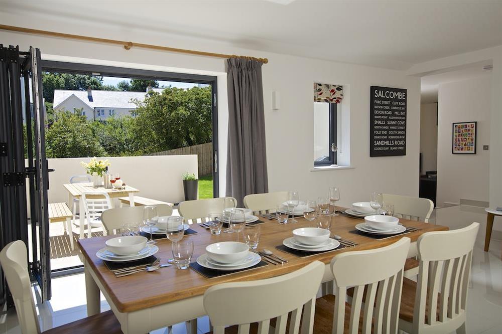 Dining area with table seating eight and doors leading out to the terrace and garden at Driftwood in , Salcombe