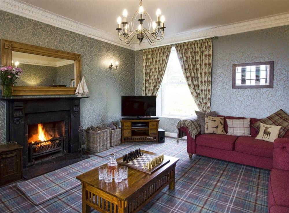 Grand living room with open fireplace at Drummuie House in Golspie, Sutherland