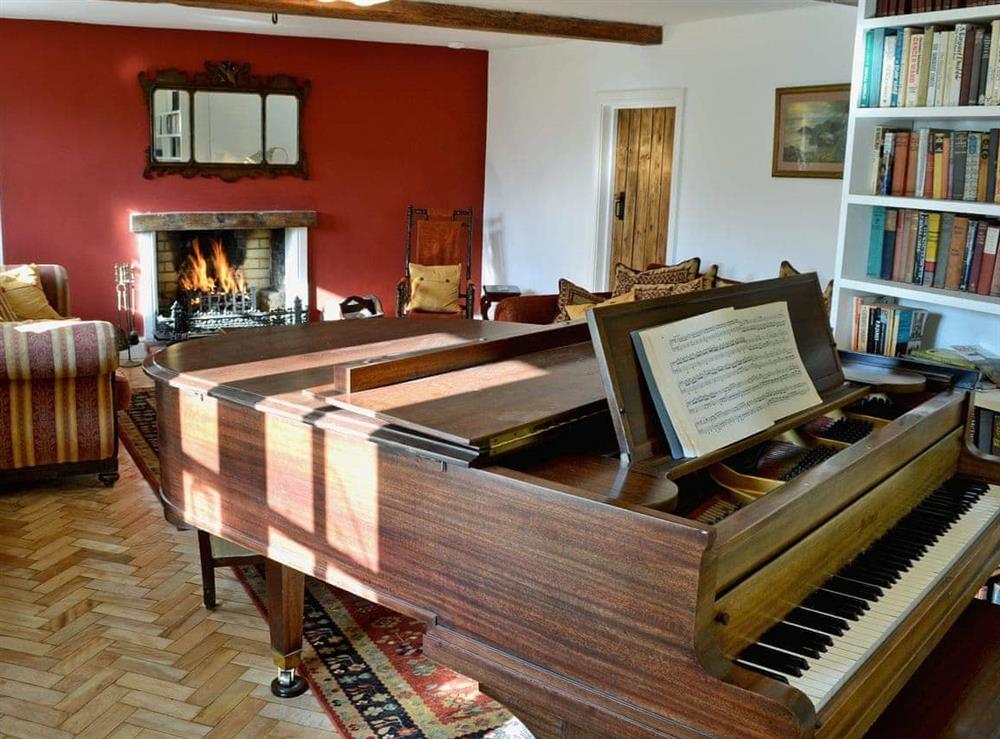 Impressive living room with open fire and baby grand piano at Dyes Cottage in Hindolveston, near Holt, Norfolk