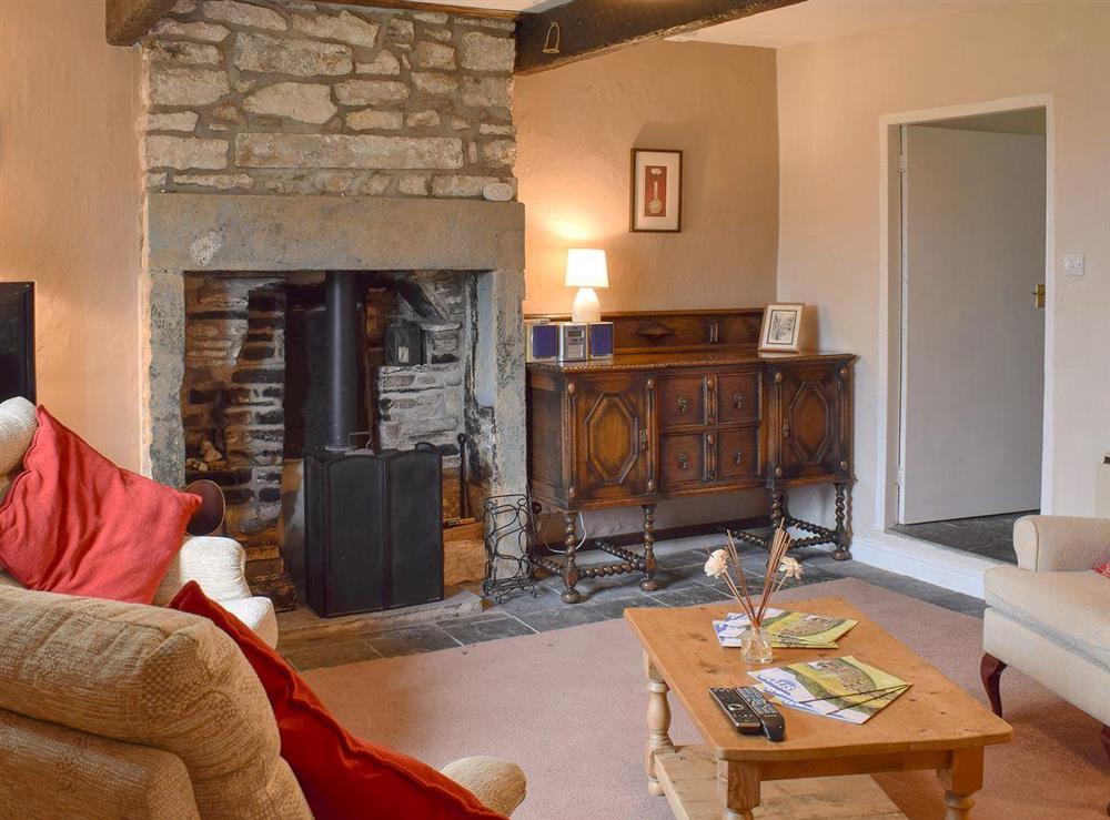 Living room, with wood burner, beams and part stone floor at East Cottage in Booze, near Reeth, North Yorkshire