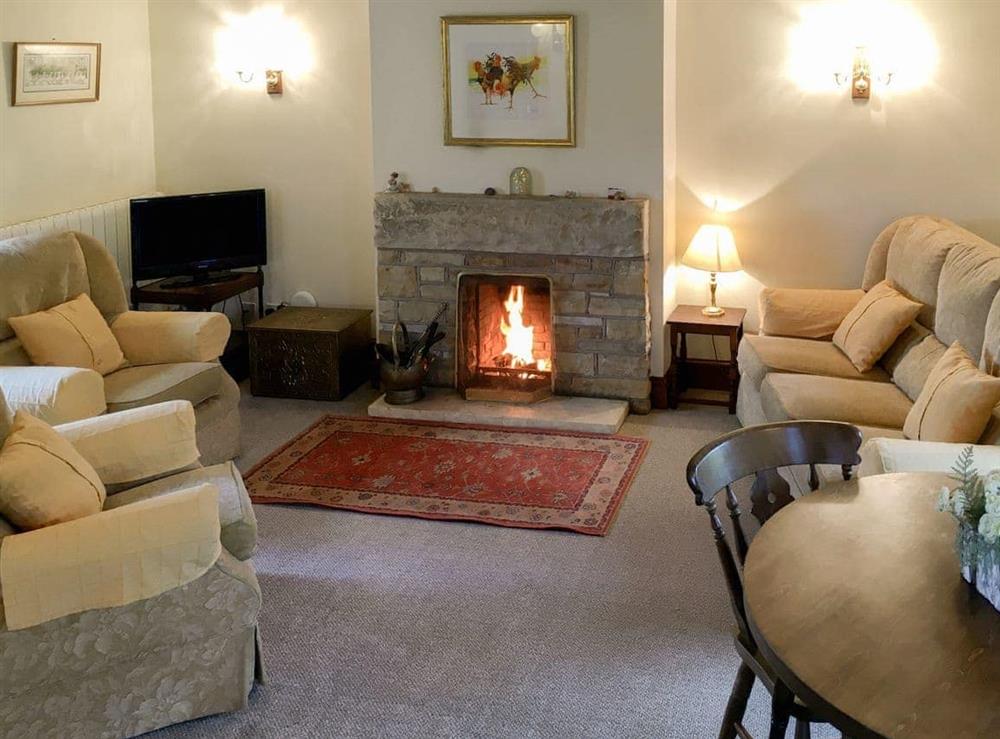 Living room with a cosy open fire at Ellarbeck Cottage in Caldbeck, near Keswick, Cumbria