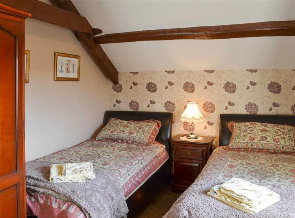Twin bedroom with beams and a sloping ceiling at Batty Barn, 