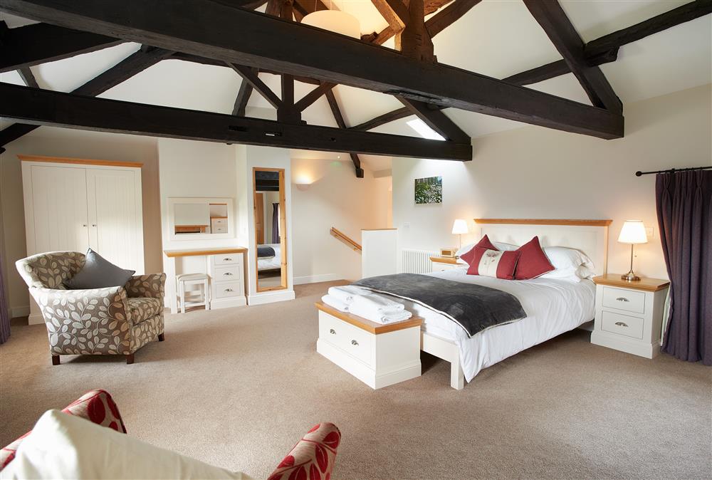 Bedroom with a 5’ king-size bed and en-suite bathroom with a roll-top bath and walk-in shower at Engineer Apartment, Netherby Hall, Longtown