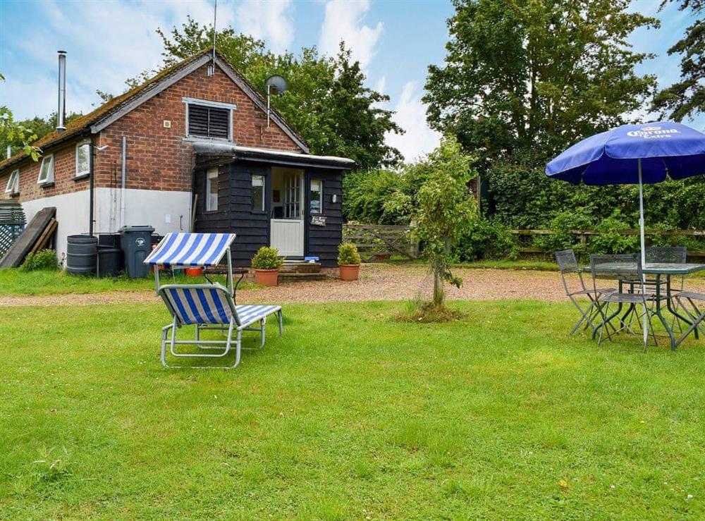Lawned grounds with sitting-out area and furniture at Evie Rose Cottage in Elsenham, near Bishop’s Stortford, Essex