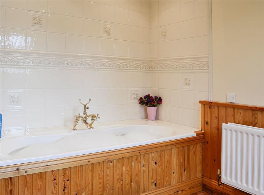 Delightful bathroom with wood panelled bath at Fairfield in Keswick, Cumbria