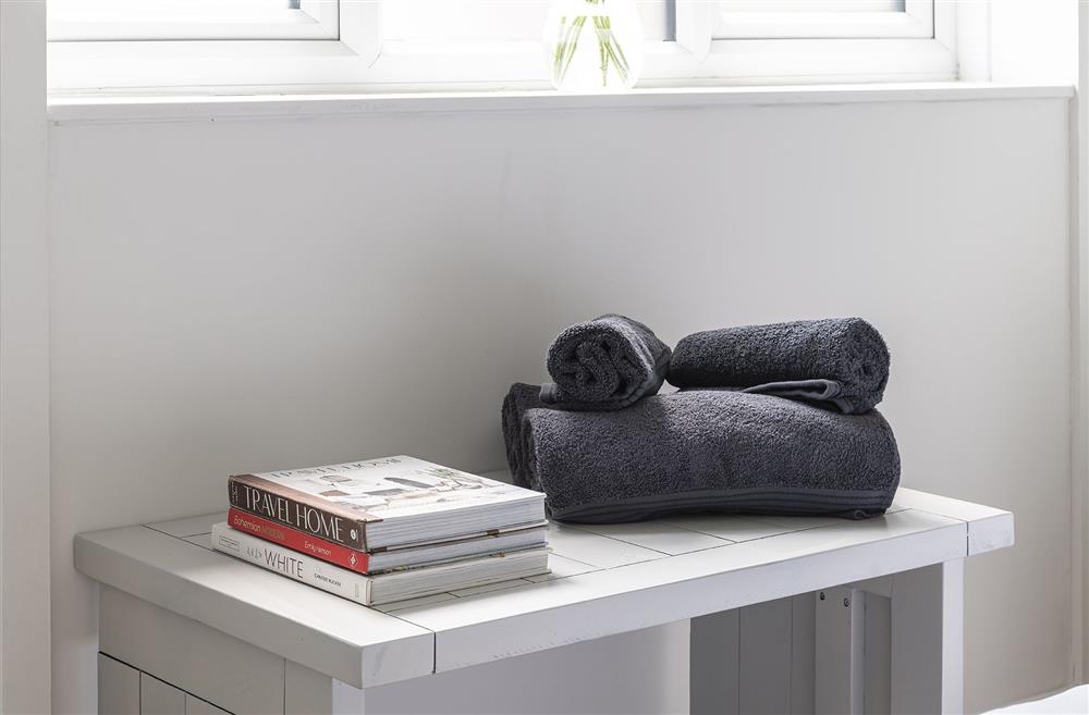 A bedside table with a stack of books and towels