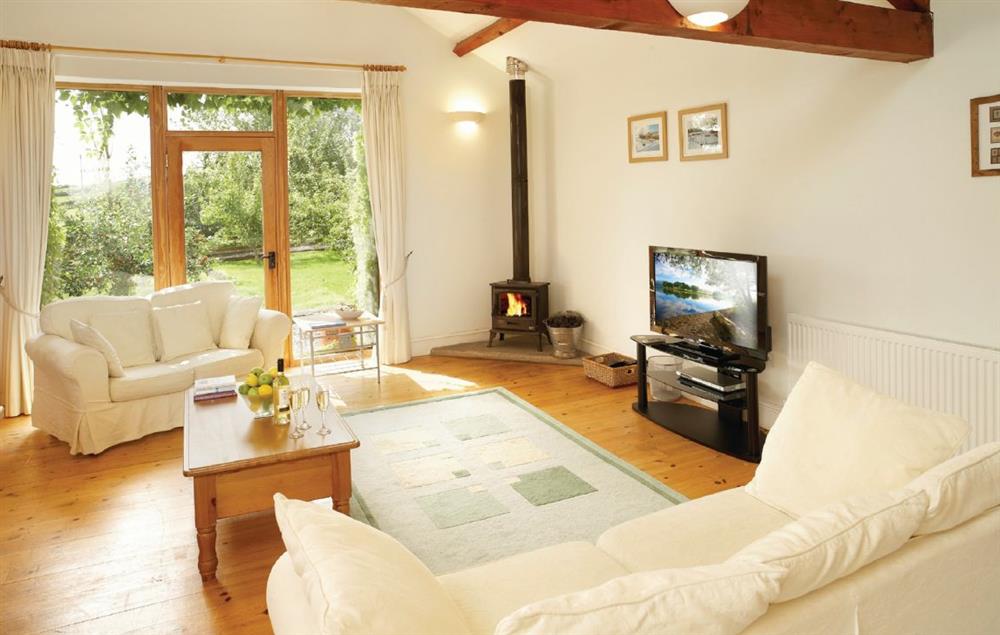 Open-plan sitting area with multi-fuel burning stove, dining area and kitchen at Fellside Barn, Broughton Beck