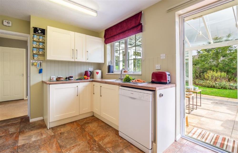 Kitchen with views of the conservatory and garden beyond at Field End, Westleton