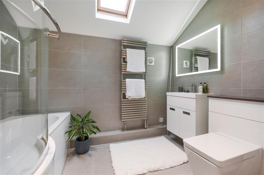 The en-suite bathroom with shaped bath and over-head shower  at Fig and Bay Cottage, Axminster