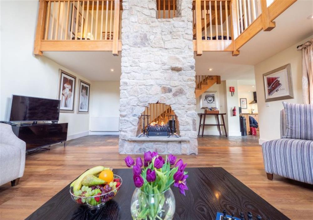 Spacious sitting room with triple height ceilings and feature stone fire place at Fingle Bridge in Chagford