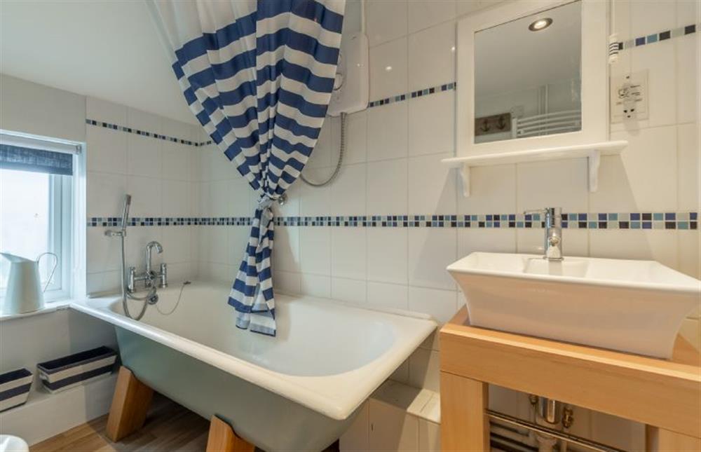 First floor: Bathroom with bath with shower over and hand held shower attachment at First & Last, Trimingham near Norwich